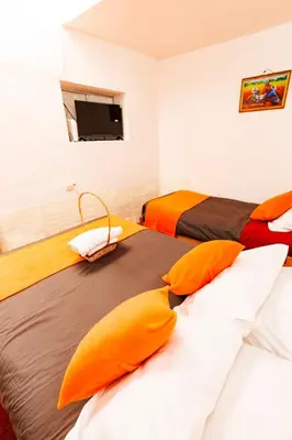 two beds with orange pillows in a room at Mayu House Inn I a minutos de la plaza in Cusco