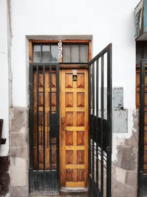 a wooden door with a sign on a building at Mayu House Inn I a minutos de la plaza in Cusco