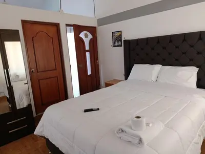 a bedroom with a white bed with a remote control on it at Hostal Ayllu con cochera in Urubamba