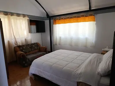 a bedroom with a bed and a chair at Hostal Ayllu con cochera in Urubamba