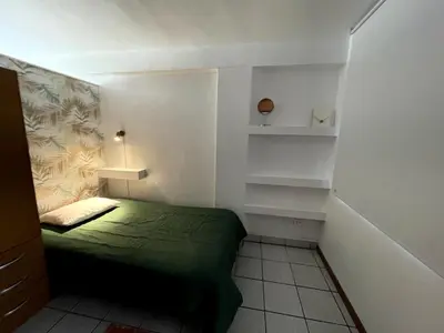 a small room with a green bed and shelves at Confortable and central in Lima
