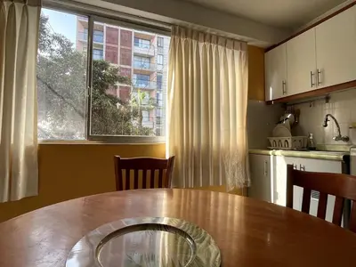 a kitchen with a wooden table and a large window at Confortable and central in Lima