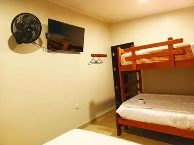 a bedroom with two bunk beds and a television at Alojamiento Oslo San Ramón in San Ramón