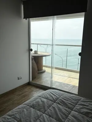 a bedroom with a view of the ocean through a glass door at Departamento en Punta Hermosa frente al mar in Punta Hermosa