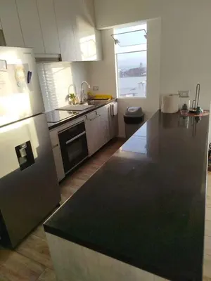 a kitchen with a black counter top and a refrigerator at Departamento en Punta Hermosa frente al mar in Punta Hermosa