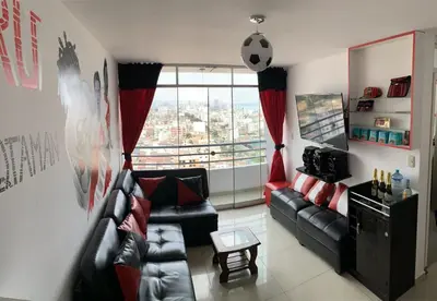 a living room with a leather couch and a large window at Departamento 03 dormitorios cerca Arena 1 in Lima