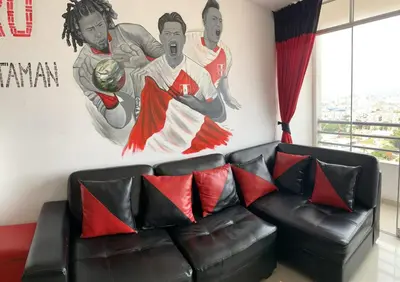 a couch in a living room with a mural of two basketball players at Departamento 03 dormitorios cerca Arena 1 in Lima