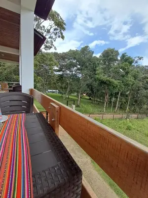 a balcony with a table and chairs and a view of a park at Cabaña BellaVista in Oxapampa