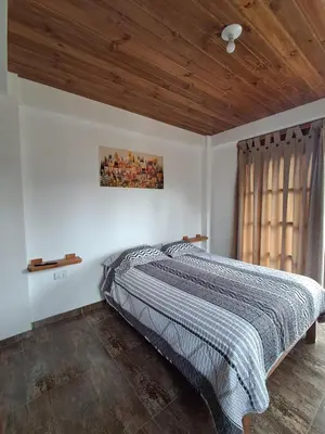 a bed in a bedroom with a wooden ceiling at Cabaña BellaVista in Oxapampa
