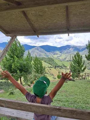 a young boy with his arms in the air looking at the mountains at Cabaña BellaVista in Oxapampa