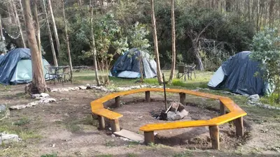 a wooden bench in a field with tents at Cusco Sana Lodge in Cusco
