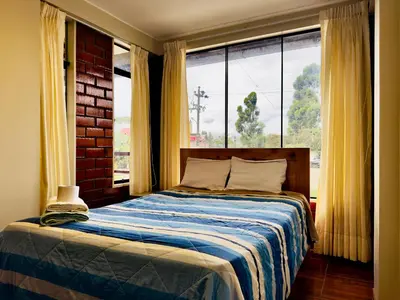 a bedroom with a bed and a large window at Casa Familiar TOVCA Oxapampa in Oxapampa