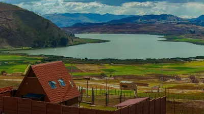 a view of a lake and a house next to a fence at Alpine Cabin Quito in Cusco