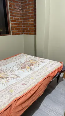 a bed sitting in a room next to a brick wall at Habitación Los Solises in Jauja