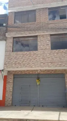 a brick building with a garage with two garage doors at Habitación Los Solises in Jauja