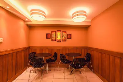 a restaurant with tables and chairs in a room with orange walls at Principe III in Cusco