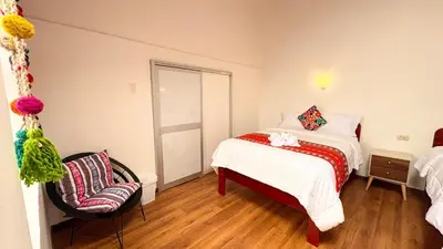 a small bedroom with a bed and a chair at Horizonte Hotels in Cusco