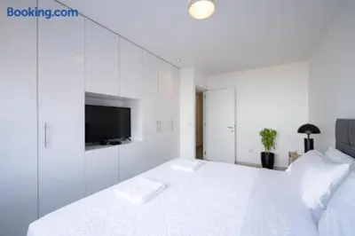 a white bedroom with a large bed and a tv at Barranco-Miraflores 2BR OceanView Modern Apt up to 6 guests! in Lima