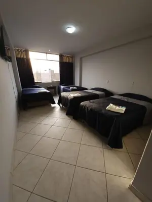a hotel room with three beds and a window at HOTEL Regency Plaza in Pisco