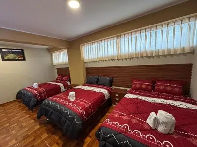 three beds in a room with red sheets at Gran Hotel Real in Huancayo