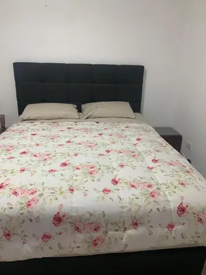 a bed with a floral comforter on it at Beach House - Condominio Asia Bonita in Asia