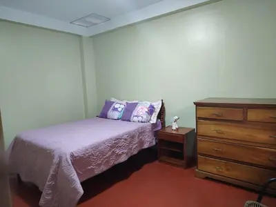 a bedroom with a bed and a wooden dresser at Posada del Carmen in Quillabamba