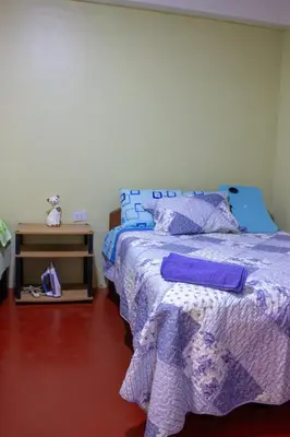 a bedroom with a bed with purple comforter at Posada del Carmen in Quillabamba