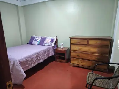 a bedroom with a bed and a dresser at Posada del Carmen in Quillabamba
