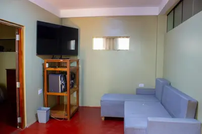 a living room with a couch and a flat screen tv at Posada del Carmen in Quillabamba
