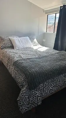 a bed with a black and white comforter and a window at Cozy room with kitchenette and private bathroom in Cusco