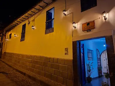 a yellow building with a door on a street at night at PUKARI WASI café hospedaje in Cusco