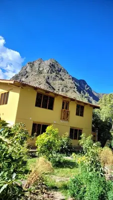 a large yellow house with a thatched roof at Lavanda lodge Ollantaytambo in Ollantaytambo