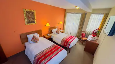 two beds in a room with orange walls at Hotel Boutique Imperial in Cusco