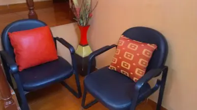 two blue chairs with a red pillow and a vase at Hostal GQ in Lima