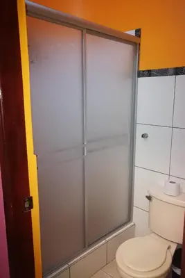 a glass shower door in a bathroom with a toilet at Hostal GQ in Lima