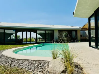 a swimming pool in front of a house at Beautiful house with pool in Oasis Bahía de Paracas in Las Palmeras