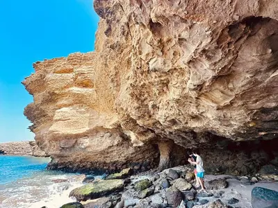 a man standing in front of a large rock cliff at Beautiful house with pool in Oasis Bahía de Paracas in Las Palmeras
