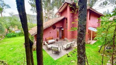 a red house with a patio in the yard at Casa Munay in Urubamba
