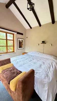 a bedroom with a large white bed with a chair at Casa Munay in Urubamba