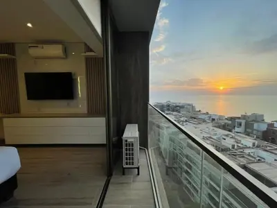 a room with a balcony with a view of the ocean at The Modern Studios by Vibrant in Lima