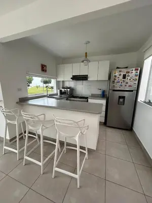 a kitchen with a counter and chairs and a refrigerator at Casa de Playa en Puerto Viejo, Condominio Kalua in San Antonio