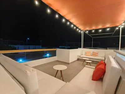 a rooftop deck with white furniture and a swimming pool at night at Casa de Playa en Puerto Viejo, Condominio Kalua in San Antonio