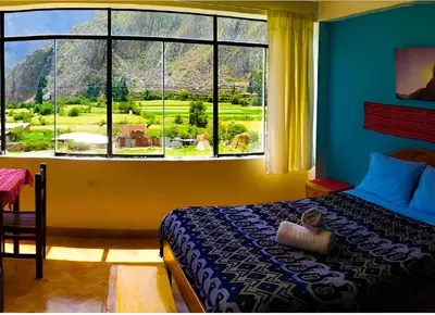 a bedroom with a bed and a large window at Lycka Wasi Hospedaje in Ollantaytambo