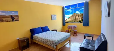 a yellow room with a bed and a chair in it at Lycka Wasi Hospedaje in Ollantaytambo