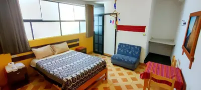 a bedroom with a bed and a blue chair at Lycka Wasi Hospedaje in Ollantaytambo