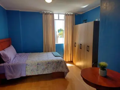 a bedroom with blue walls and a bed and a table at Casa Quevedo in Ica