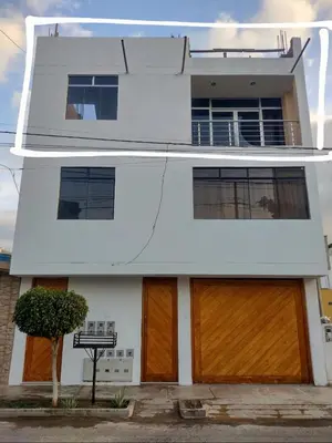 a white house with two brown garage doors at Casa Quevedo in Ica
