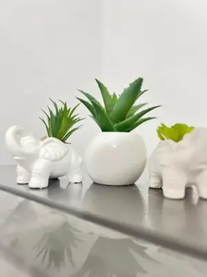 a table with three white ceramic elephants and a plant at Habitación equipada en san juan de Lurigancho in Lima