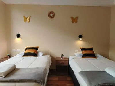two beds in a room with butterflies on the wall at Apu Garden Lodge in Urubamba