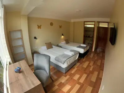 a room with two beds and a couch and a table at Apu Garden Lodge in Urubamba